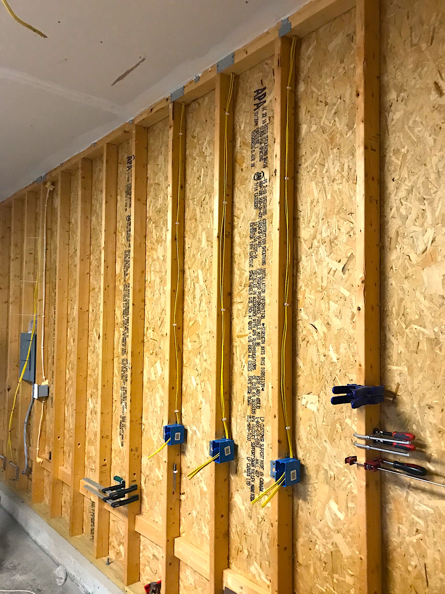 An unfurnished garage wall with electrical cables traveling up and down walls
