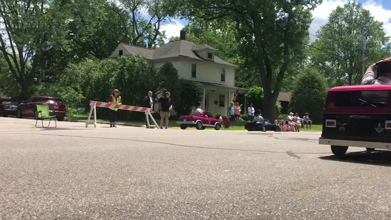 Several people with fez hats drive around in small gas powered vehicles in a choreographed formation.